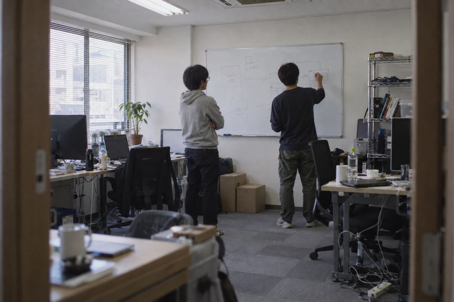 ホワイトボードの前で業務の流れを整理するメンバー